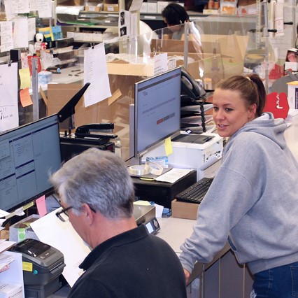 two EMS staff members working on computers talking to one another